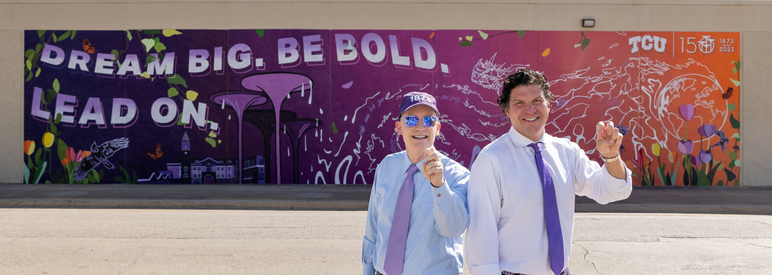 Chancellor Victor Boschini and President Daniel Pullin stand in front of TCU's campus mural
